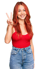 Young redhead woman wearing casual clothes showing and pointing up with fingers number two while smiling confident and happy.