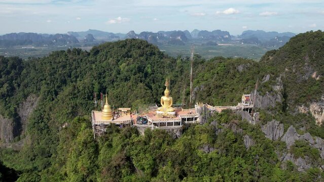 Backward reveal drone footage of viewpoint on the top of a rock on sunny day. Tiger Cave Temple, Krabi, Thailand.