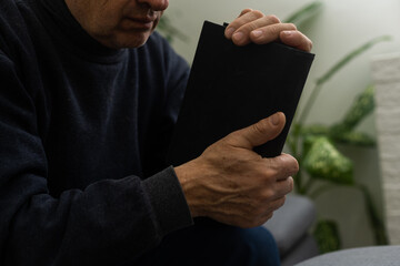 Senior man praying, holding Bible