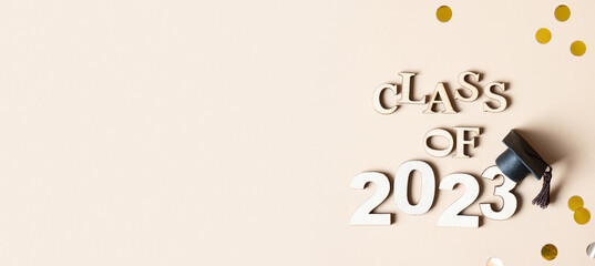 Class of 2023 concept. Wooden number 2023 with graduated cap with tinsel top view. Banner format
