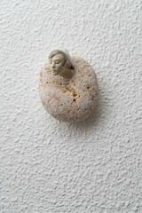 Cabeza de cerámica y piedra de rio, sobre pared estucada en blanco