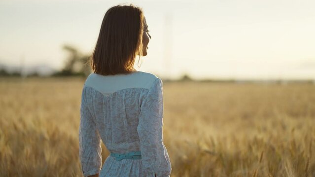 Beautiful image of woman silhouette among wheat field during sunset or sunrise. Female standing alone and enjoying summertime. Ripe harvest time