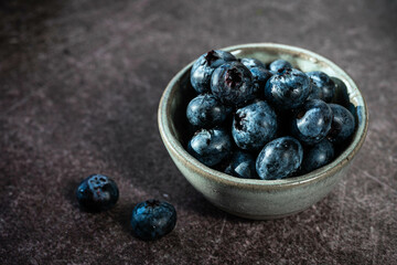 Blueberries in ceramic bowl on dark background 