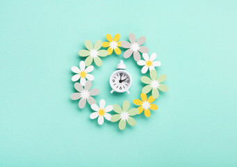 White Alarm Clock and Spring Daisy Flowers on Blue Background