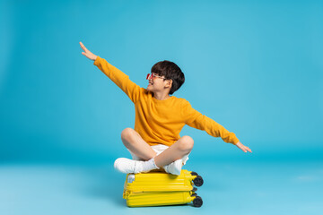 Asian boy pulling suitcase on blue background