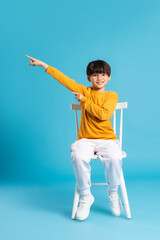 Portrait of sitting boy, isolated on blue background