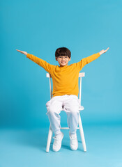 Portrait of sitting boy, isolated on blue background