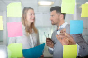 businessmen and women reading post-it on the windows