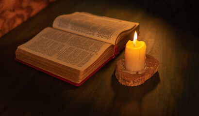 Bible illuminated by candlelight on a wooden table