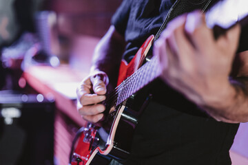 Man playing the guitar during a concert, no faces shown