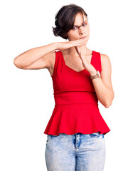 Beautiful young woman with short hair wearing casual style with sleeveless shirt doing time out gesture with hands, frustrated and serious face