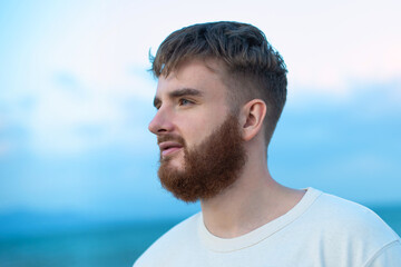 Serious young man on the beach, summer sea with beard 