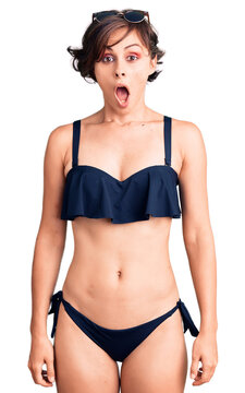 Beautiful young woman with short hair wearing bikini scared and amazed with open mouth for surprise, disbelief face