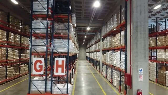 4K Aerial view of warehouse. Wide angle shooting of warehouse and shelves. Symmetrical view of placed up palleted goods. Forest of shelves. Stock video.  