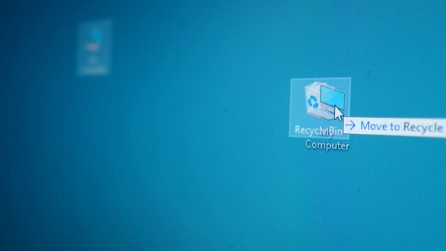 Close-up image of a PC desktop on a monitor screen. The mouse cursor moves across the screen and moves the My Computer icon to the Recycle Bin. User deletes his computer.