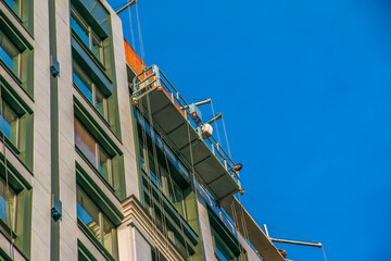 Suspended platform, construction cradle hanging on building. Installation and repair work. Building...