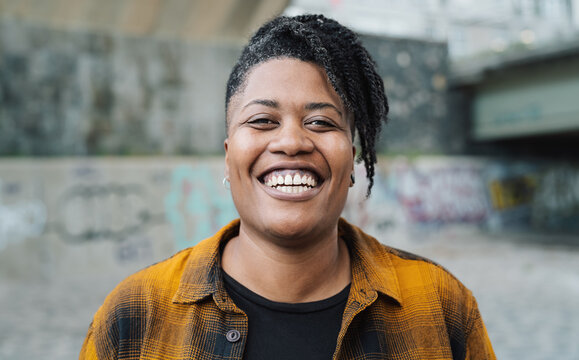 Happy African woman smiling in front of a camera in the city