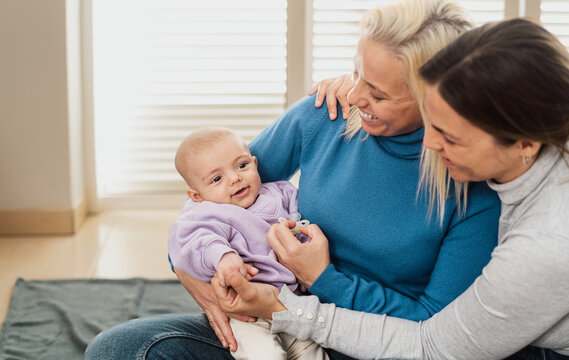 Happy Lesbian Couple Having Tender Moments With Their Small Baby At Home - LGBT Family Concept