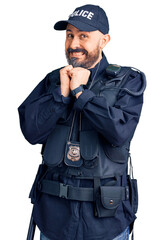 Young handsome man wearing police uniform laughing nervous and excited with hands on chin looking to the side