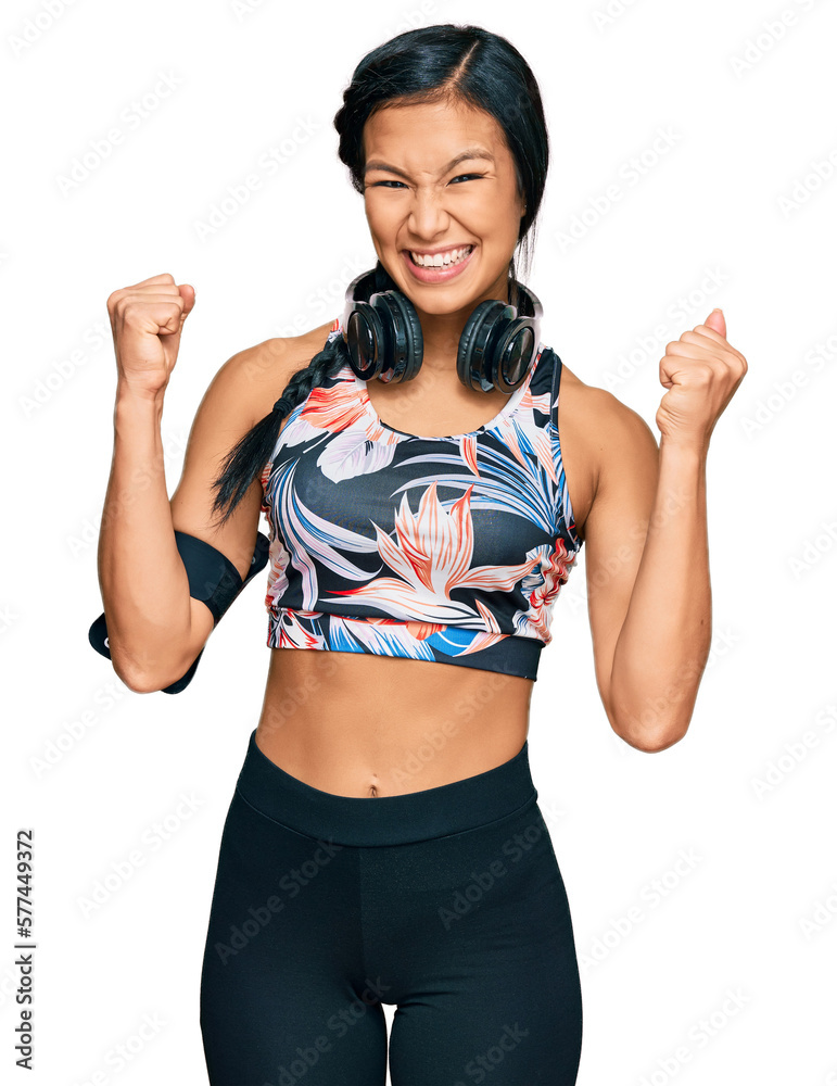 Sticker Beautiful hispanic woman wearing sportswear and headphones celebrating surprised and amazed for success with arms raised and open eyes. winner concept.