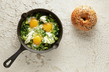 Green shakshuka with frshly baked bagel. Fried eggs in a cast iron pan. Traditional meal of the...