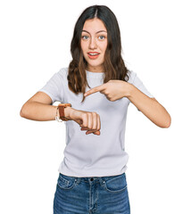 Young beautiful woman wearing casual white t shirt in hurry pointing to watch time, impatience, upset and angry for deadline delay