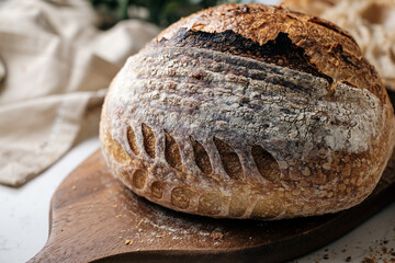 Artisan Batard Sourdough healthy Bread with leaf scoring. Open crumb high hydration Sourdough bread set on white table.