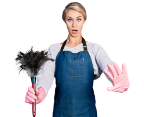 Beautiful young blonde woman wearing apron holding cleaning duster doing stop gesture with hands palms, angry and frustration expression