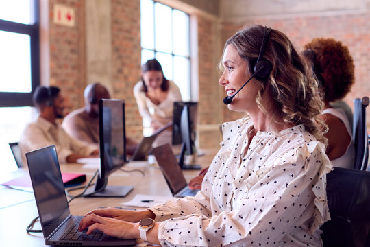 Multi-Cultural Business Team Wearing Headsets Working In Customer Support Centre