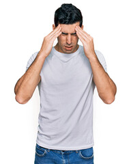 Naklejka premium Handsome hispanic man wearing casual white t shirt with hand on head for pain in head because stress. suffering migraine.