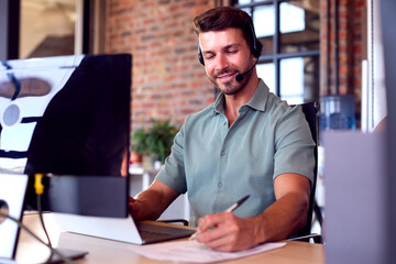 Fototapeta premium Businessman Wearing Headset At Computer In Customer Support Centre