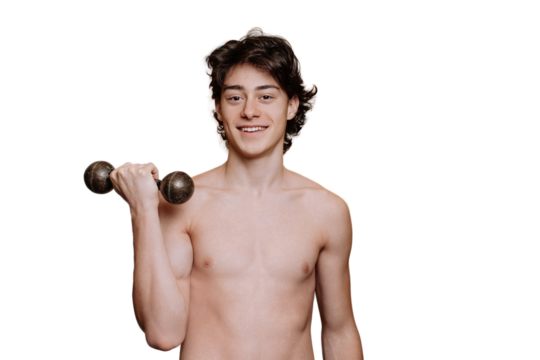 Fit young guy toothy smiles looks at camera holds dumbbell stands against transparent background. Cheerful caucasian boy in perfect shape. Mockup, gym, fitness, workout. Strong teenager posing.