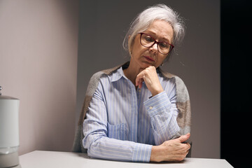 Sad elderly lady sits alone at a table