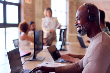 Multi-Cultural Business Team Wearing Headsets Working In Customer Support Centre