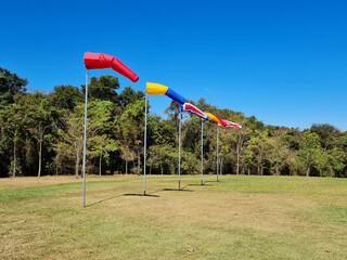Fototapeta na wymiar five colorful windsocks in a green field with trees.