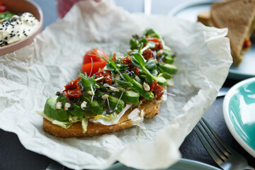 Gourmet avocado toast served with dried tomatoes and micro greens for breakfast in restaurant
