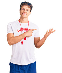 Young handsome man wearing lifeguard t shirt and whistle amazed and smiling to the camera while presenting with hand and pointing with finger.