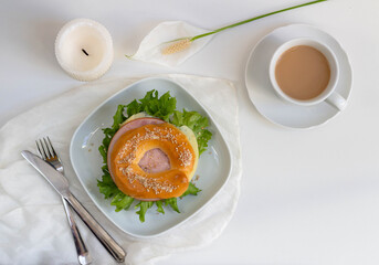 Sandwich with lettuce, cheese and ham on a plate. A cup of coffee. Top view.