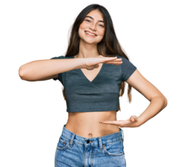 Young beautiful teen girl wearing casual crop top t shirt gesturing with hands showing big and large size sign, measure symbol. smiling looking at the camera. measuring concept.