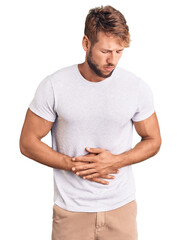 Young caucasian man wearing casual white tshirt with hand on stomach because indigestion, painful illness feeling unwell. ache concept.