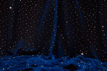 Aesthetic, elegant dark blue tulle fabric with sequins on black background. Starry night...