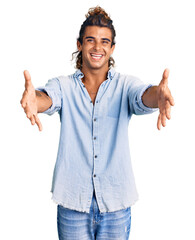 Young hispanic man wearing summer style looking at the camera smiling with open arms for hug. cheerful expression embracing happiness.