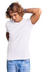 Young hispanic man wearing casual white tshirt suffering of neck ache injury, touching neck with hand, muscular pain
