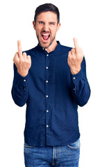 Young handsome man wearing casual shirt showing middle finger doing fuck you bad expression,...