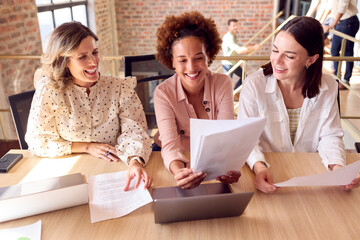 Female Multi-Cultural Business Team Meeting Around Laptop In Office