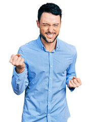 Hispanic man with beard wearing casual business shirt very happy and excited doing winner gesture with arms raised, smiling and screaming for success. celebration concept.