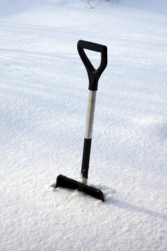 Metal shovel with black handle shovel javed deep in the snow on smooth snow field