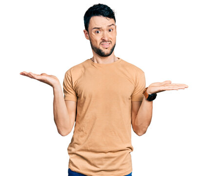 Hispanic man with beard wearing casual t shirt clueless and confused with open arms, no idea concept.