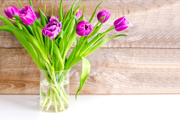 Violet purple tulips colorful bouquet in vase. Beautiful tenderness flowers macro.Spring floral romantic gift card wooden background.Flower shop florist design ,Womens,Valentines,Mother day concept