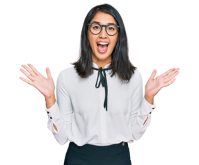 Beautiful asian young woman wearing business shirt and glasses celebrating victory with happy smile and winner expression with raised hands